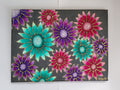 A canvas painting featuring a vibrant pattern of flowers in teal green, magenta pinks, and purples with gold outlines on a dark charcoal grey shimmer background, hung on a white wall. Original acrylic canvas painting with 3D sculptured flowers by Cathy's Art*