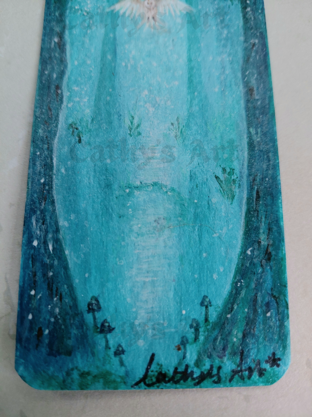 A close-up of a painted artwork featuring a teal and turquoise forest scene, small dark mushrooms are near the bottom, and a white owl at the top. The painting is signed in black at the lower right. original acrylic painting on bookmark by Cathy's Art*