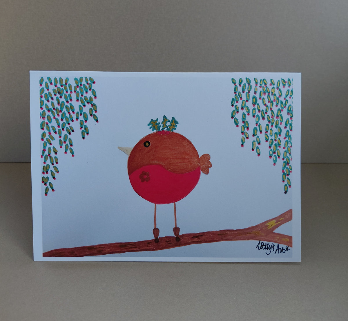 A festive printed artwork Christmas card featuring a round robin stood on a branch with a flower on its belly, holly on its head and leafy foliage hangs down either side of the robin, this has red berries on. Original artwork & printed by Cathy's Art*