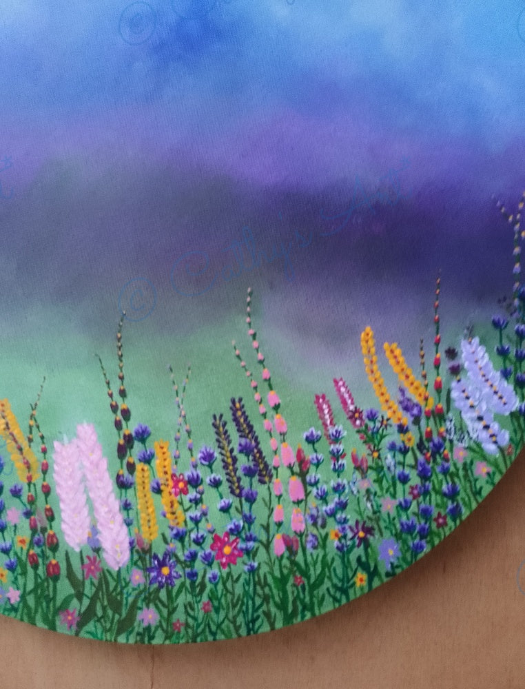 A close-up of a painted canvas showing a field of colourful wildflowers against a blue-to-green gradient sky. The painting includes purple, pink, yellow, orange, white and green tones. Original acrylic painting