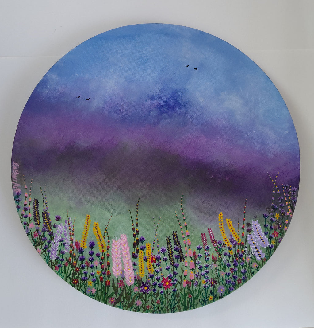A circular canvas painting featuring a vibrant wildflower meadow under a blue and purple sky, with birds flying in the distance, shown against a plain white background. Original acrylic canvas painting by Cathy's Art*