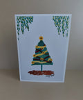 A printed artwork Christmas Card with a sunflower Christmas tree with sunflowers and tinsel. Leavy foliage hangs above the tree. Original artwork & printed by Cathy's Art*