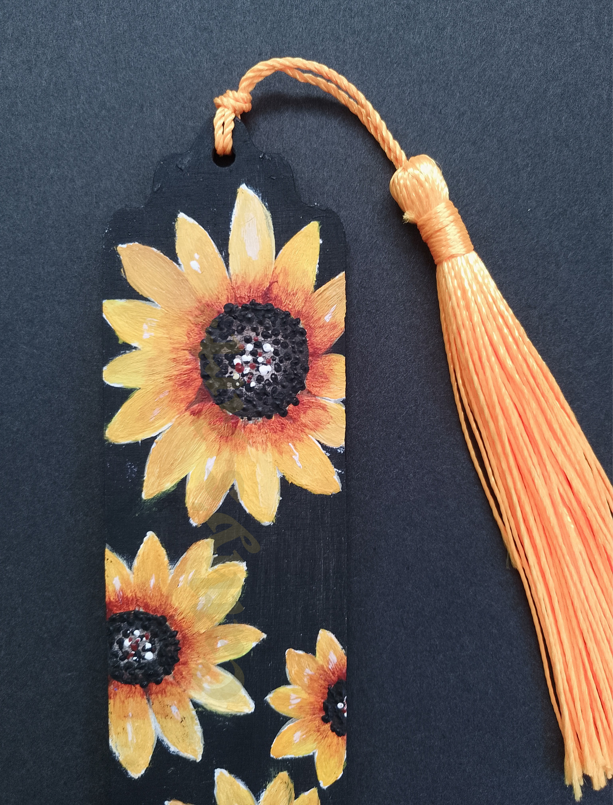 A close up of a hand painted bookmark featuring yellow sunflowers on a black background, to the right is a yellow tassel. Original acrylic painted bookmark by Cathy's Art*