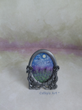 An ornate oval metal picture frame with floral rose details on the sides, holding a miniature landscape painting of a lavender field under a blue sky with the sun, displayed on a textured lilac background with a watermark 'Cathy's Art *'. Original miniature framed painting by Cathy's Art*