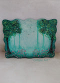 A hand-painted wooden plaque featuring a whimsical forest scene with green trees, a misty teal sky, birds flying and small pink flowers, displayed against light background. Original acrylic painting on wooden plaque by Cathy's Art*