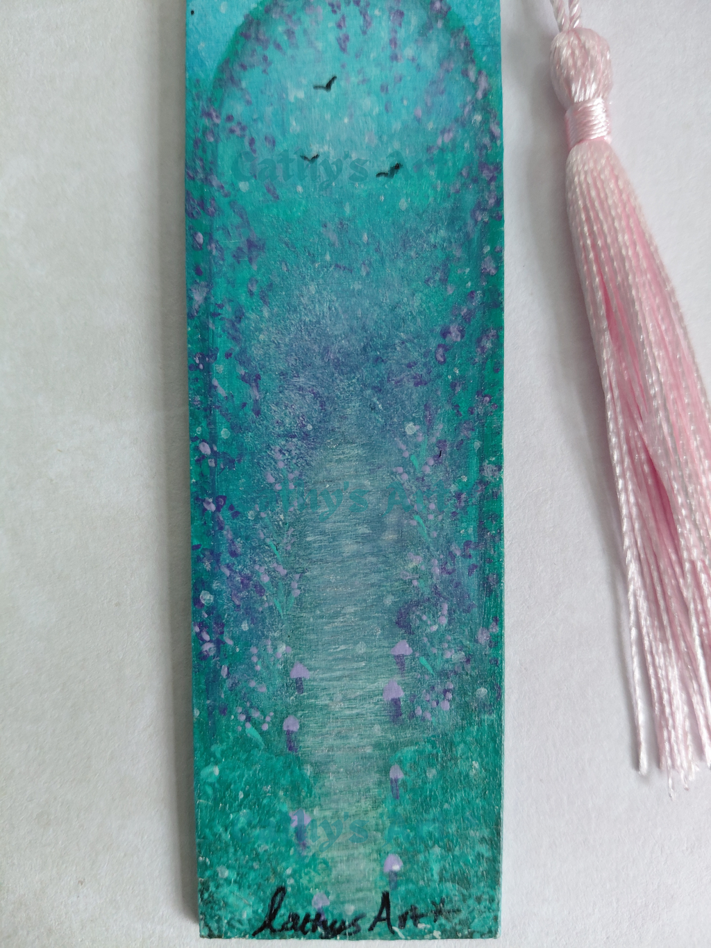 A close up of a hand painted bookmark with a a pathway lined with tiny lilac mushrooms, a flowering arch and birds in the sky. On a light coloured background. Original acrylic hand painted bookmark by Cathy's art*